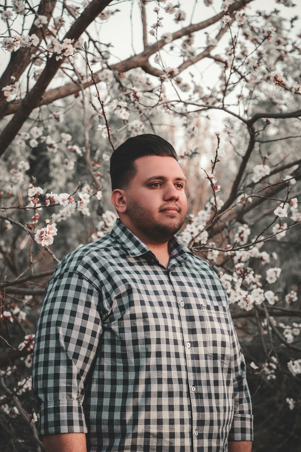 a man standing in front of a tree with white flowers