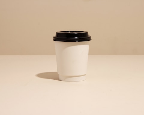 Minimalist photo of a coffee cup on a white table with soft natural light.