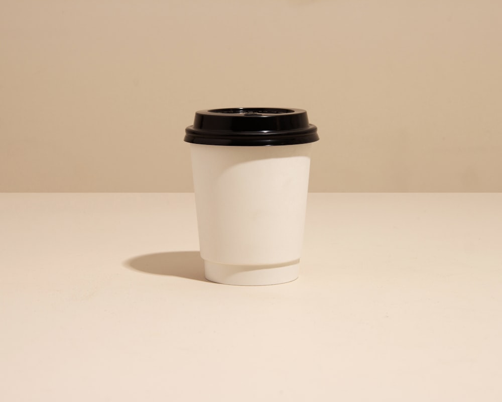 a white coffee cup with a black lid