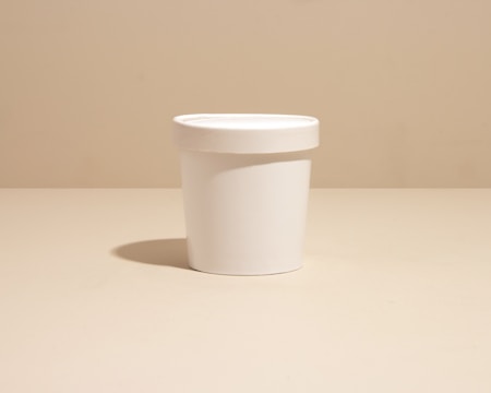 Plastic rigid pot container for cream with matching lid on a white background