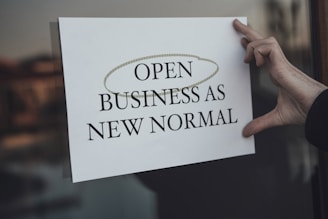 a person holding a sign that says open business as new normal