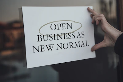 a person holding a sign that says open business as new normal