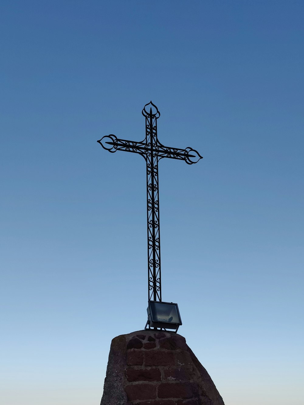 a large metal cross on top of a brick wall