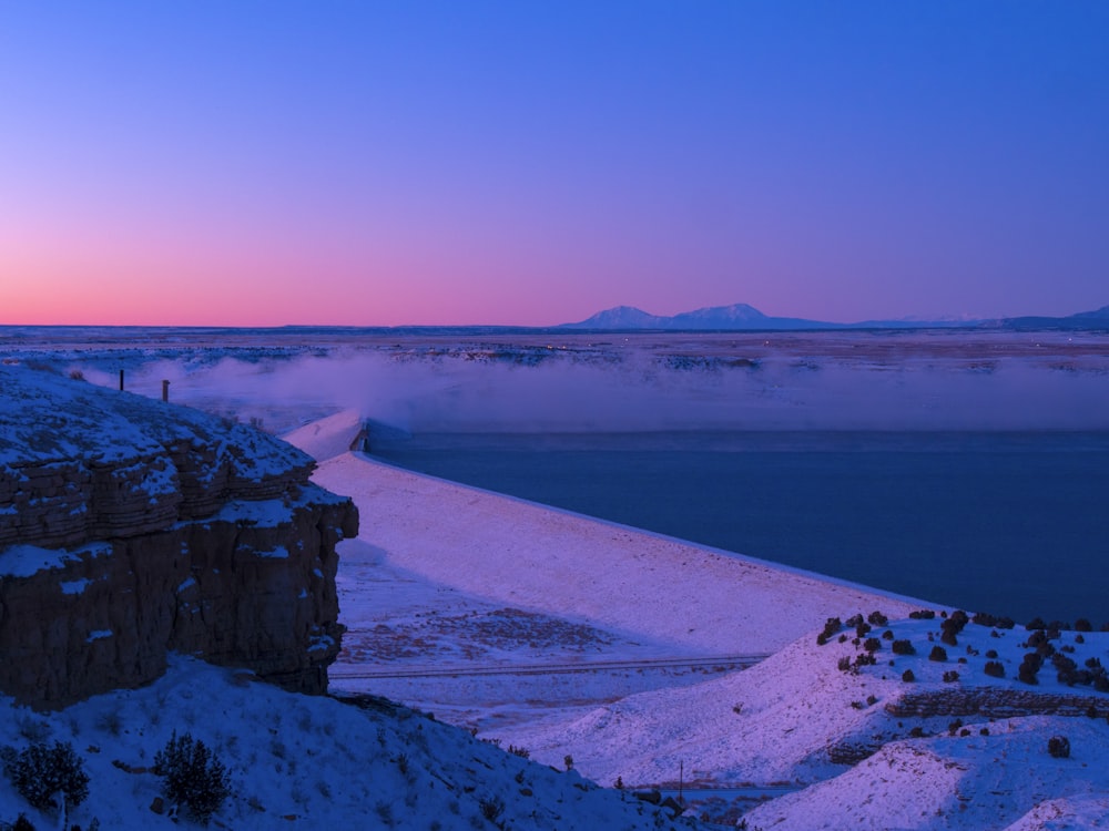 o sol está se pondo sobre uma paisagem nevada