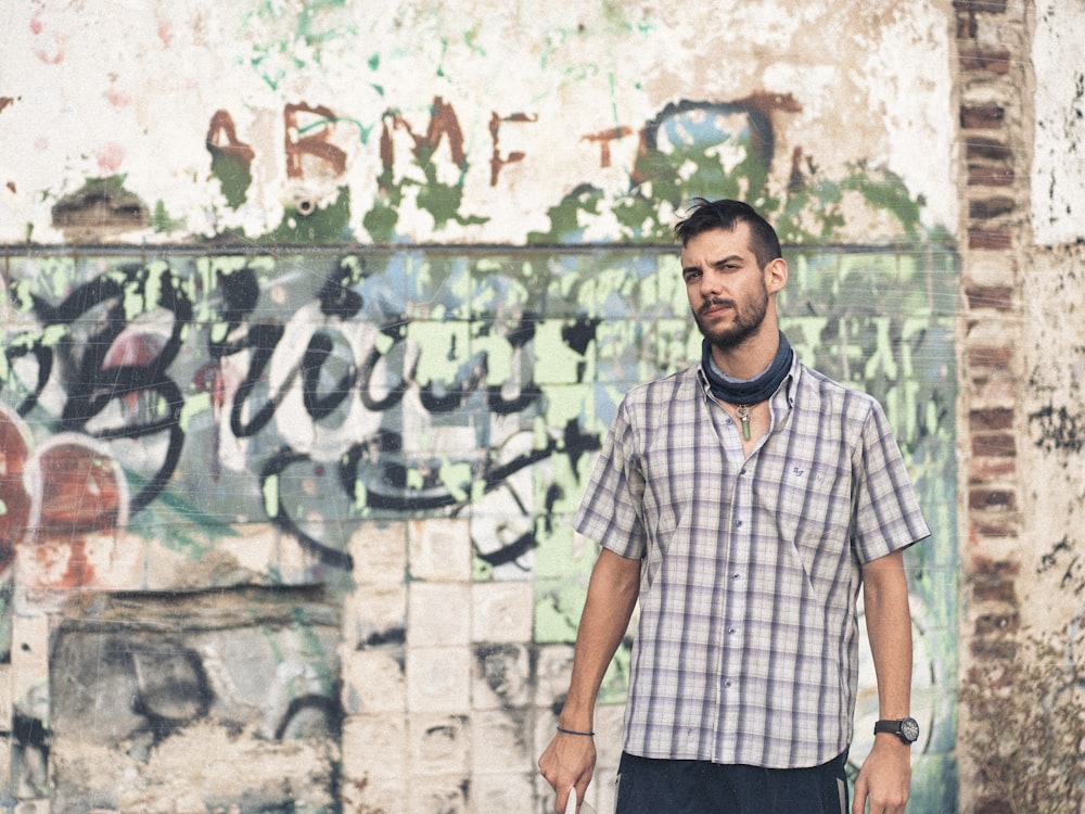 a man standing in front of a graffiti covered wall