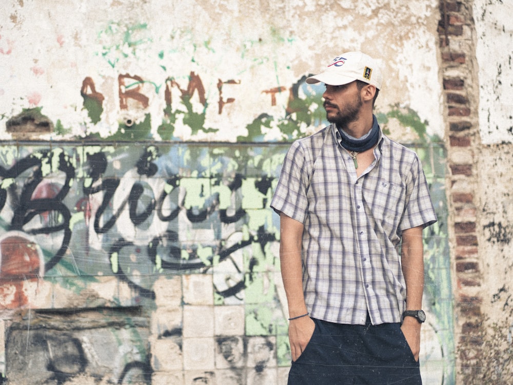 a man standing in front of a graffiti covered wall