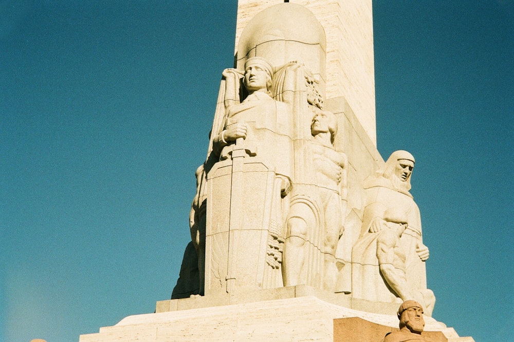 a tall monument with statues on it against a blue sky