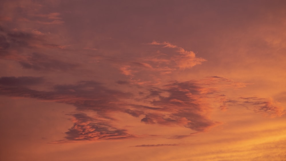 a plane flying in the sky at sunset