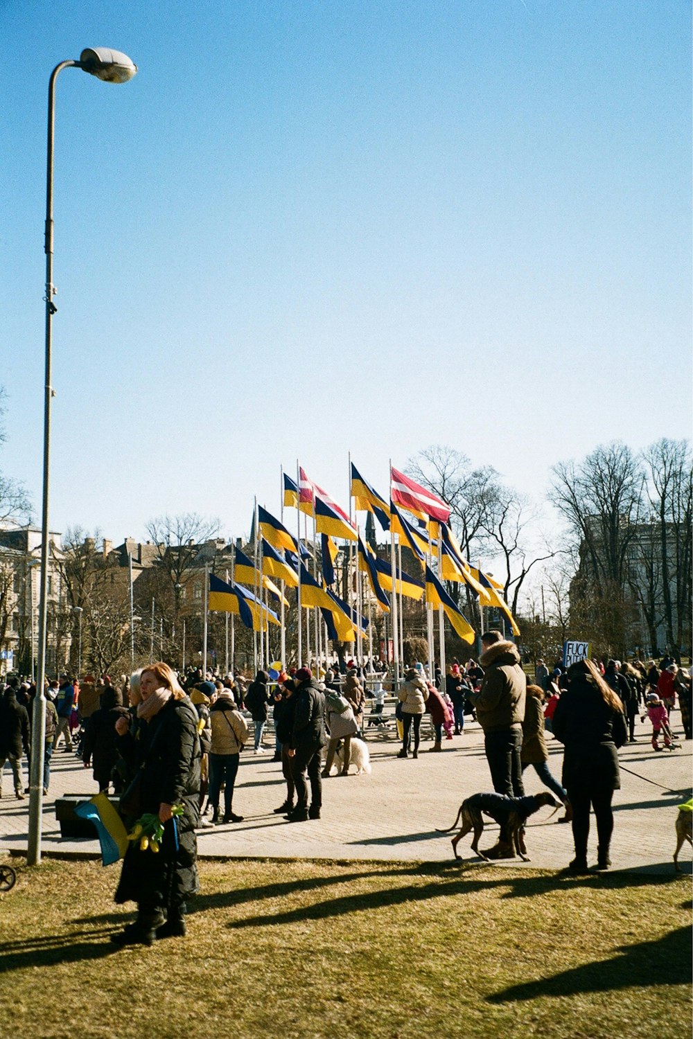 a crowd of people walking down a street next to flags