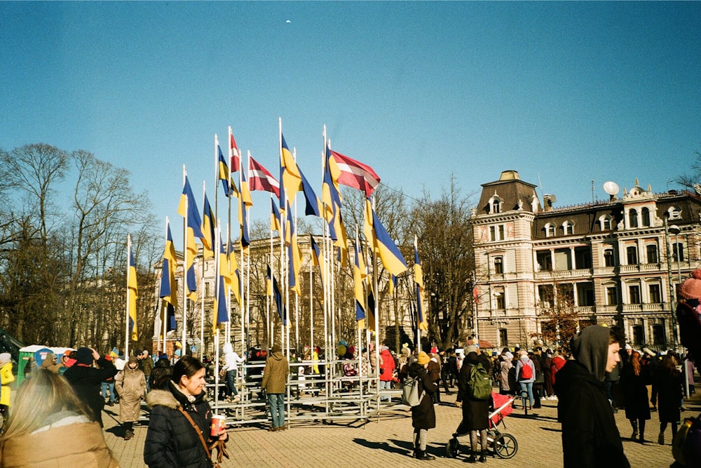 a crowd of people standing around a building with flags