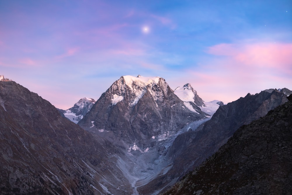 a view of a mountain range with a moon in the sky