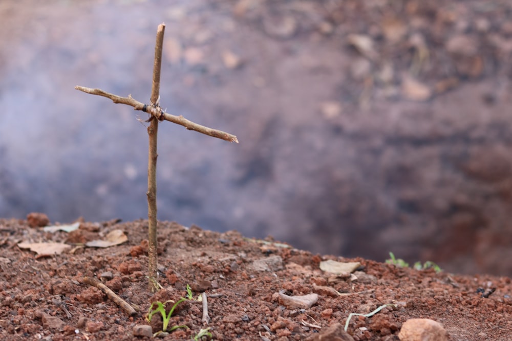 a small cross sitting on top of a dirt field