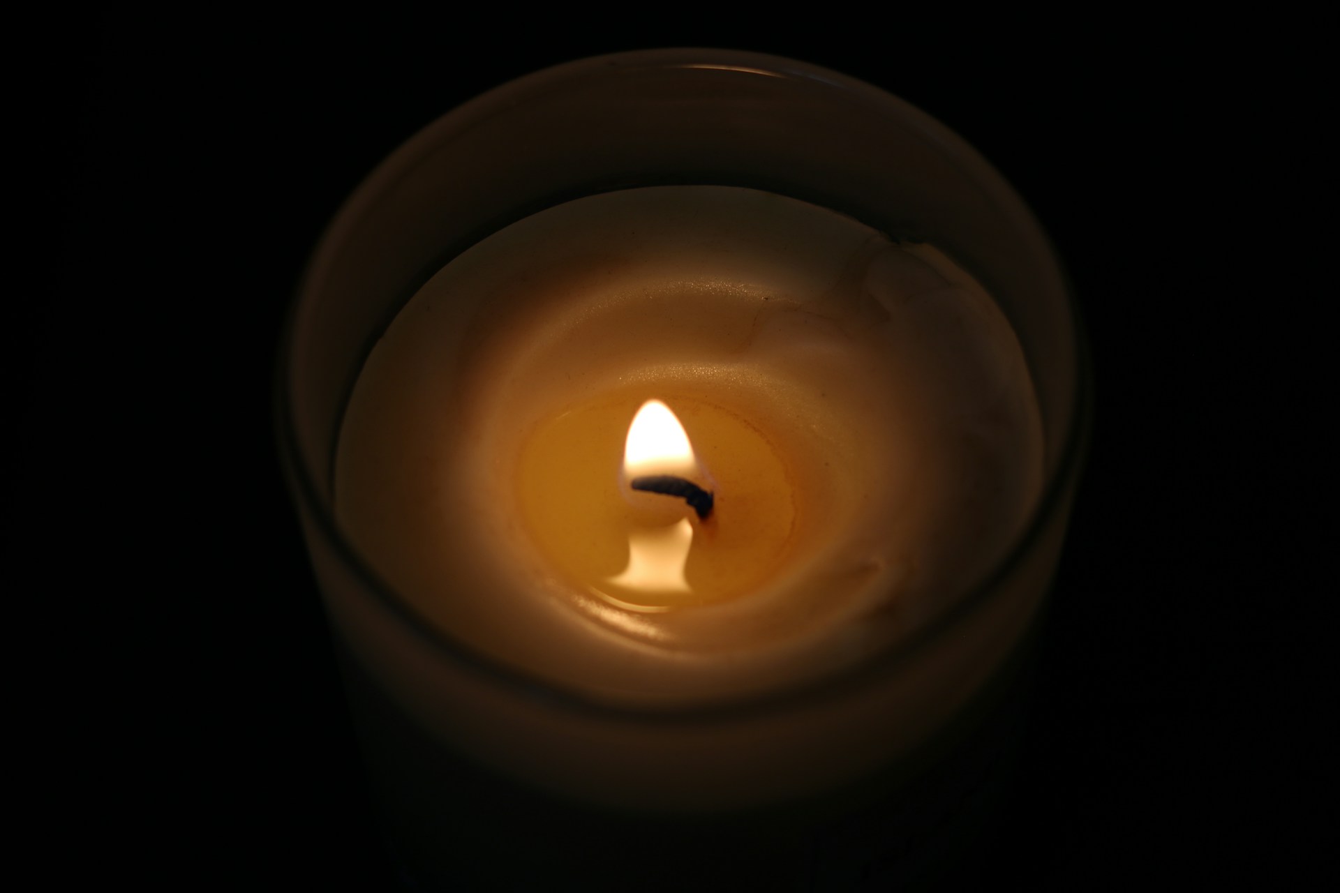a lit candle with a black background