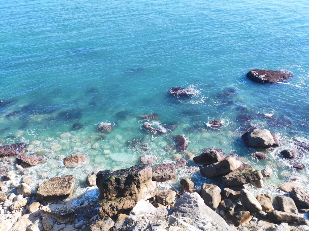 a rocky beach with clear blue water and rocks