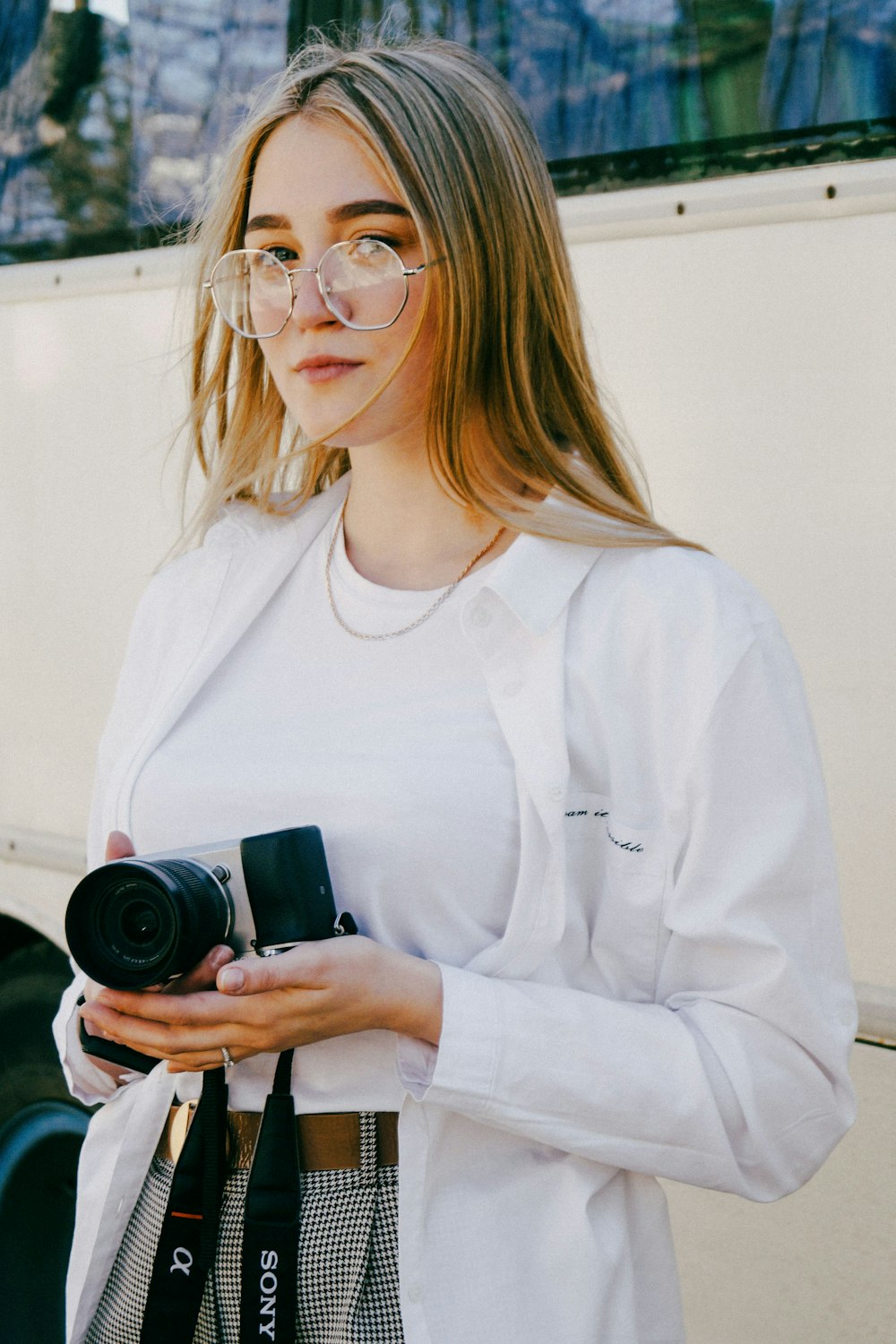 a woman holding a camera and wearing glasses