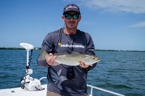 a Florida man holding a fish on a boat in a Florida lake