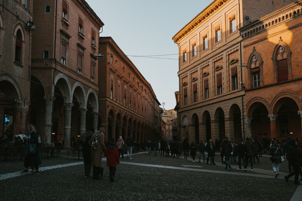 a group of people walking down a street next to tall buildings