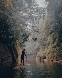 A person navigating a raft through a lively river surrounded by lush Indonesian jungle.