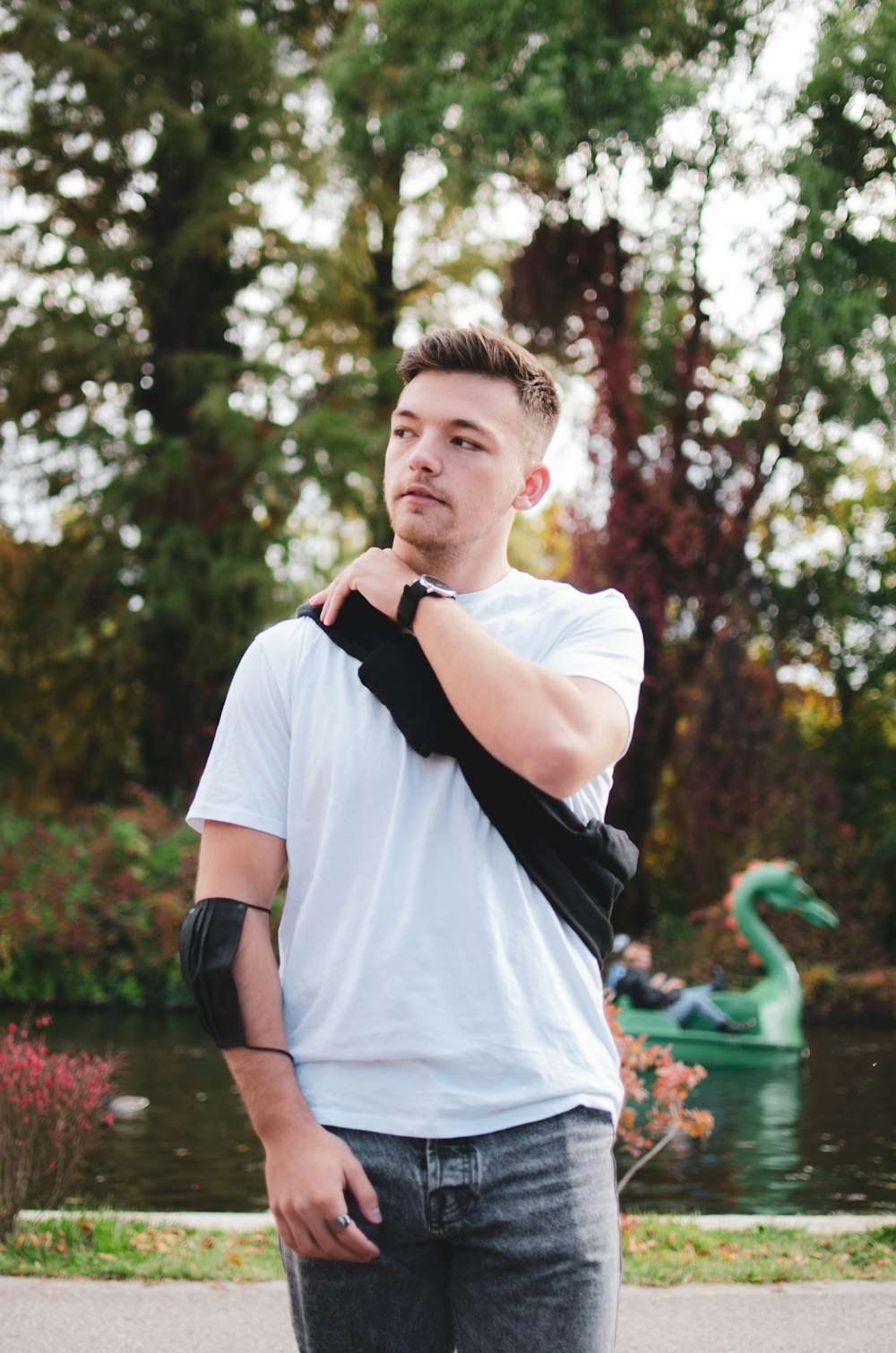 a man standing in front of a pond with a skateboard