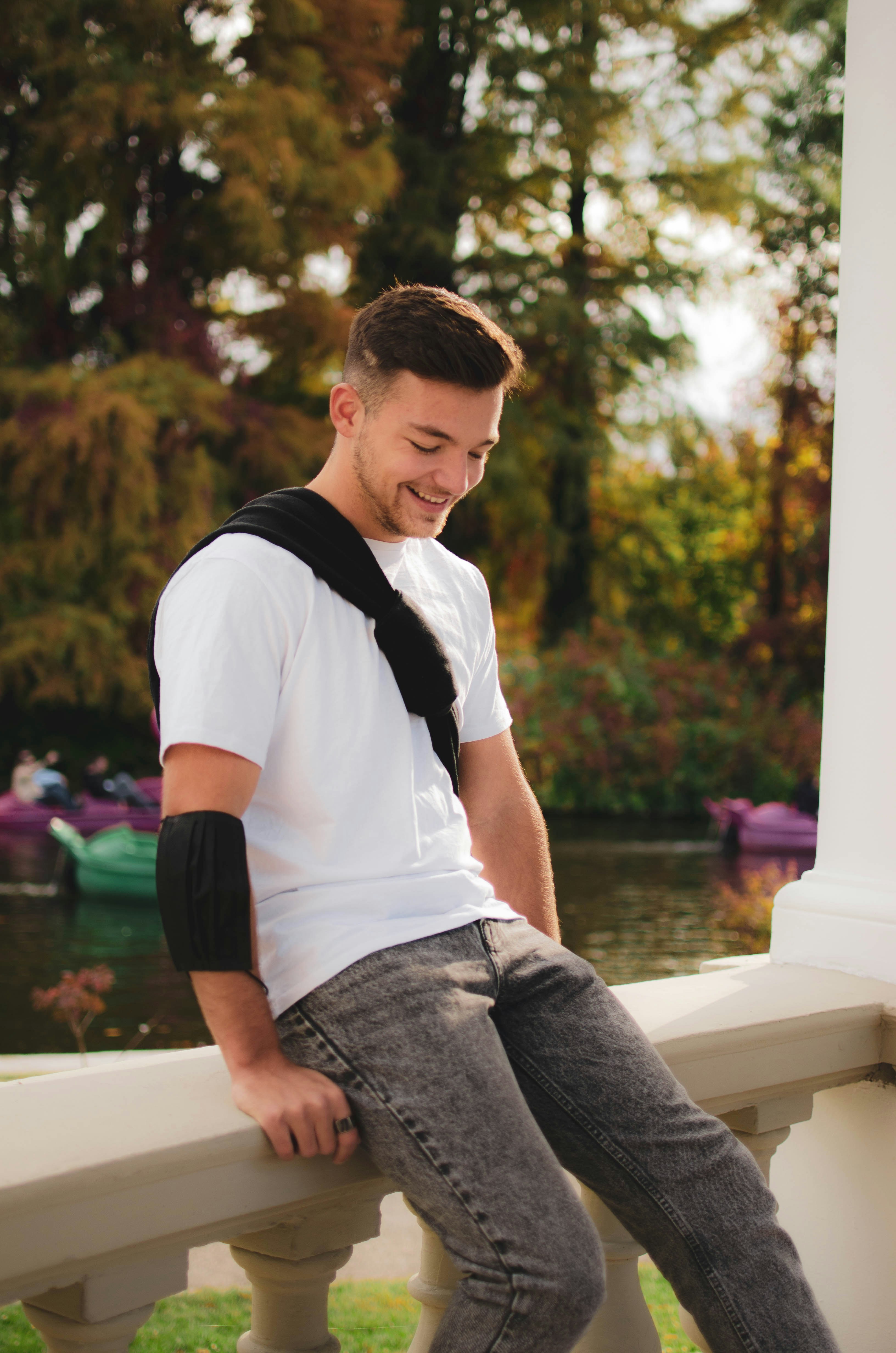 Un jeune homme assis sur un rebord avec sa main dans sa poche