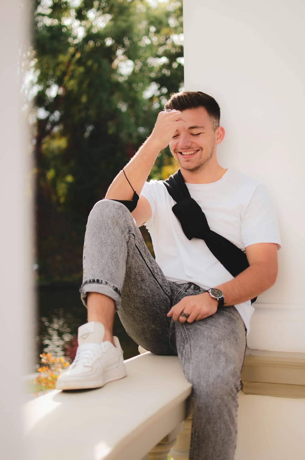 a man sitting on a ledge with his hand on his head