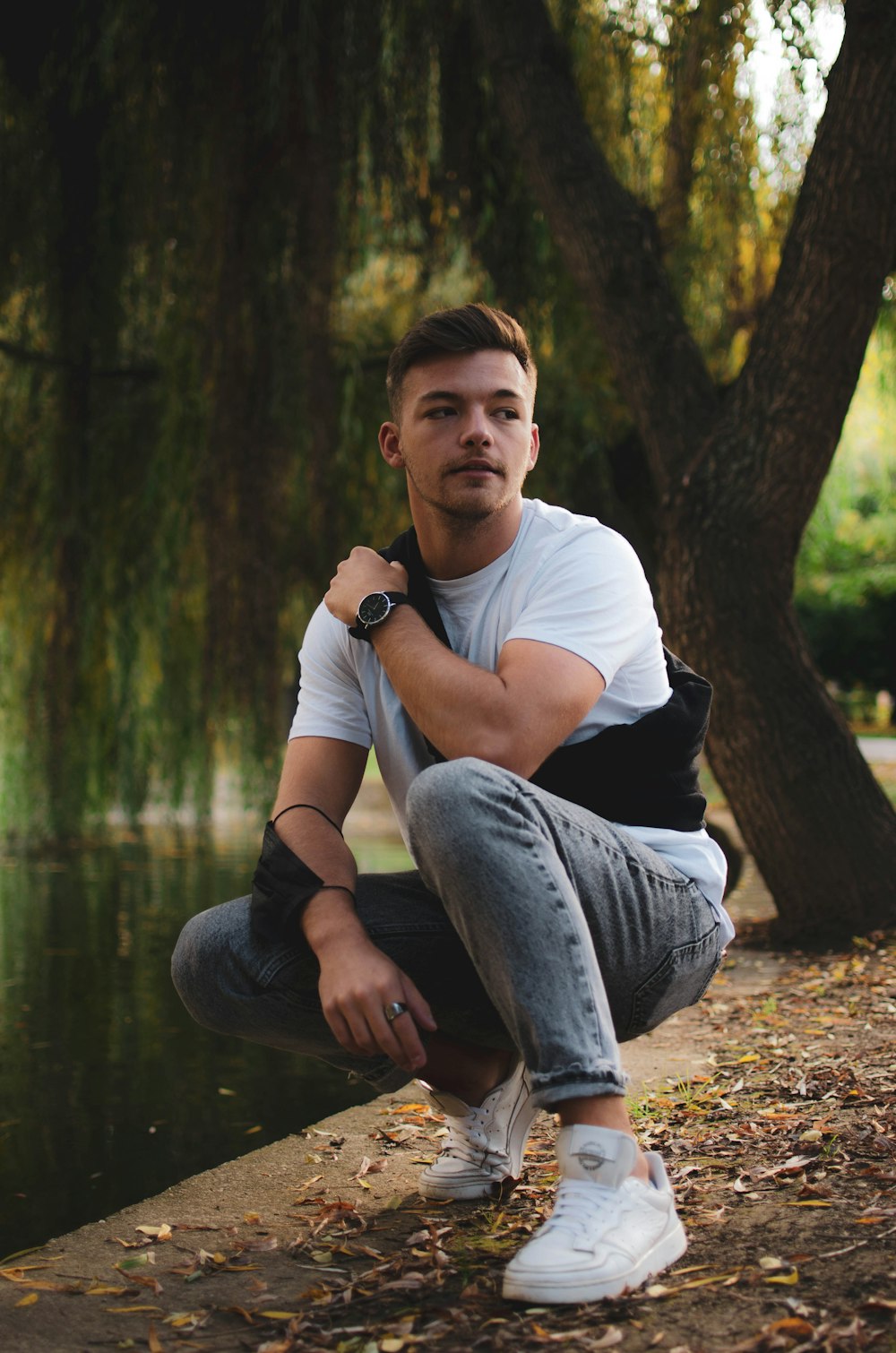 a man sitting on the ground next to a tree