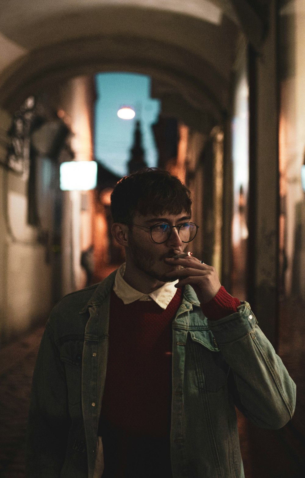 a man standing in an alley smoking a cigarette