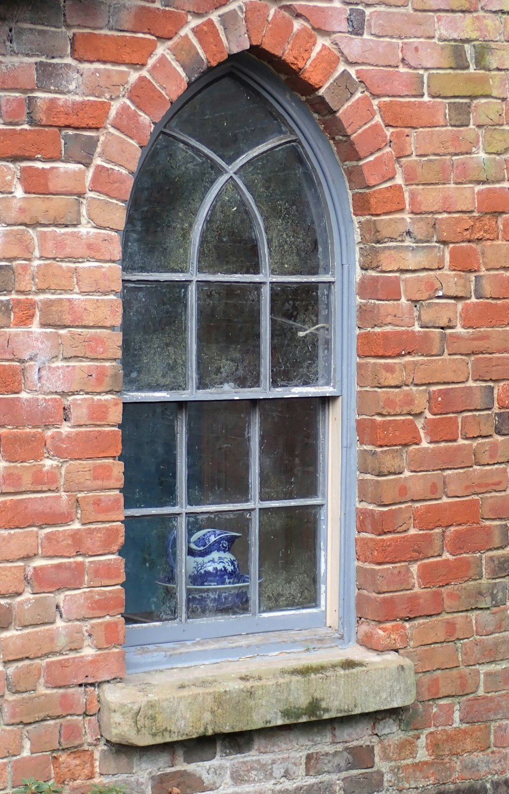 a window with a blue vase sitting in the middle of it