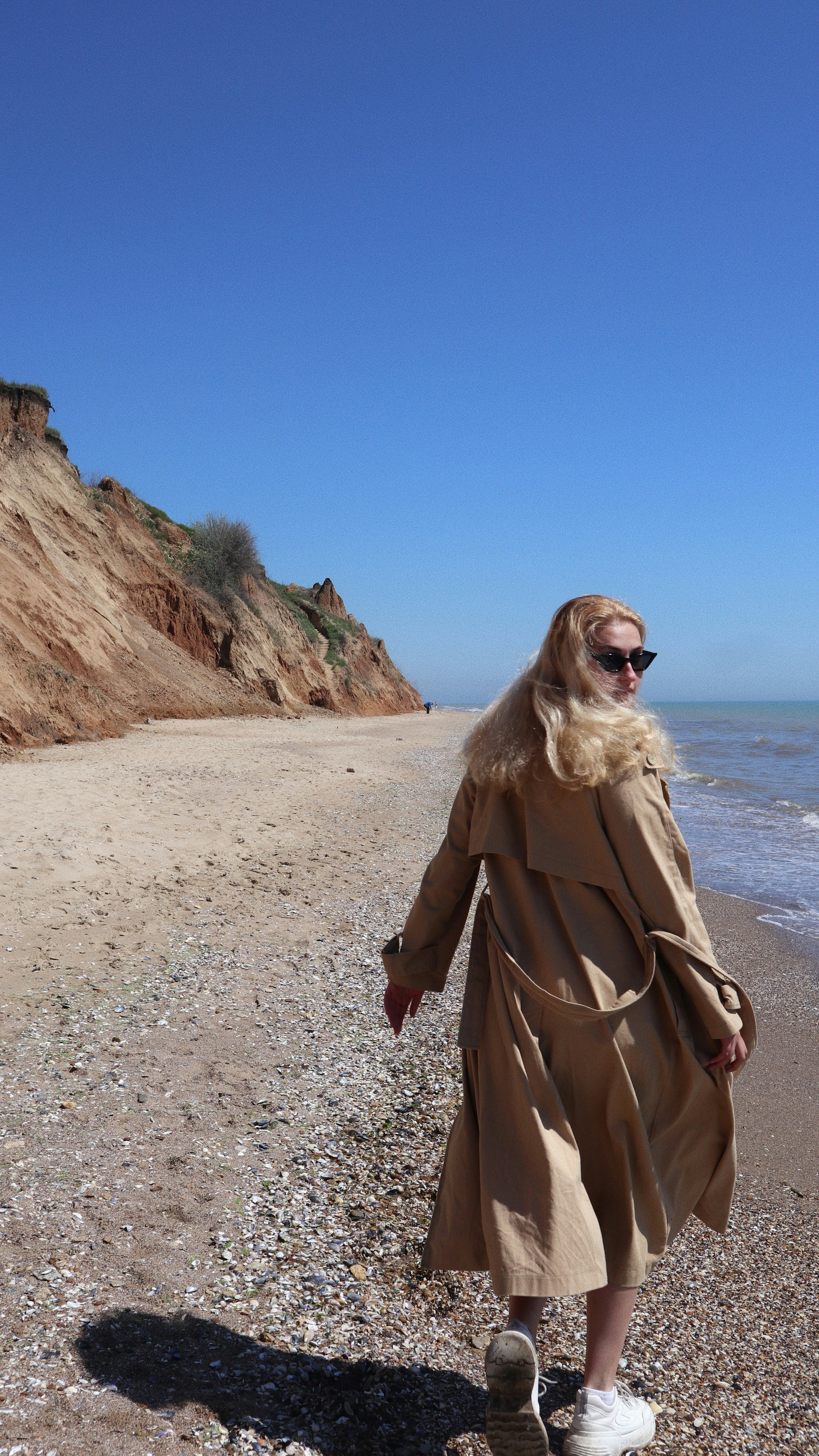 a woman walking on a beach next to the ocean