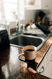 A warm, inviting kitchen scene with sunlight streaming through a window, a wooden table set with fresh ingredients and a steaming cup of tea.