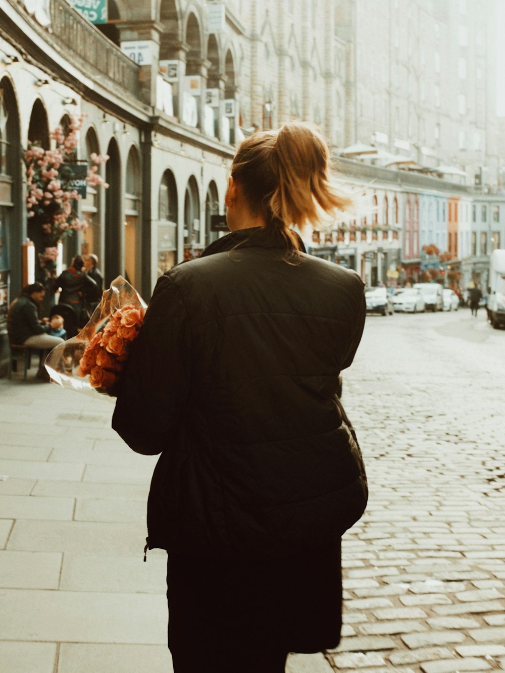 a woman walking down a street holding a bouquet of flowers