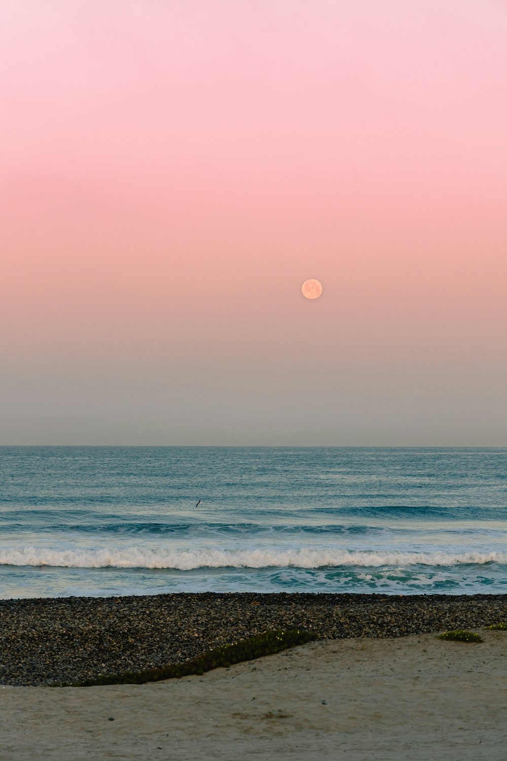 the sun is setting over the ocean and the beach