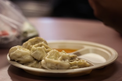 A steaming plate of colorful, protein-filled momos with dipping sauce on the side.