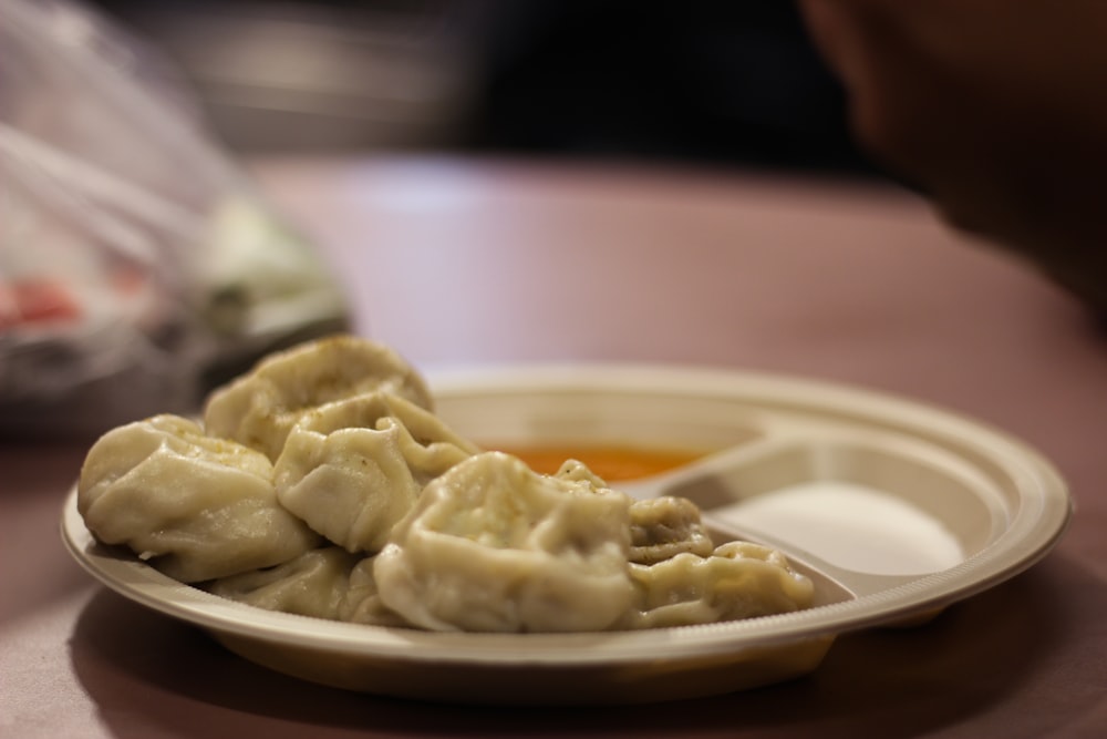 a plate of dumplings with dipping sauce on a table