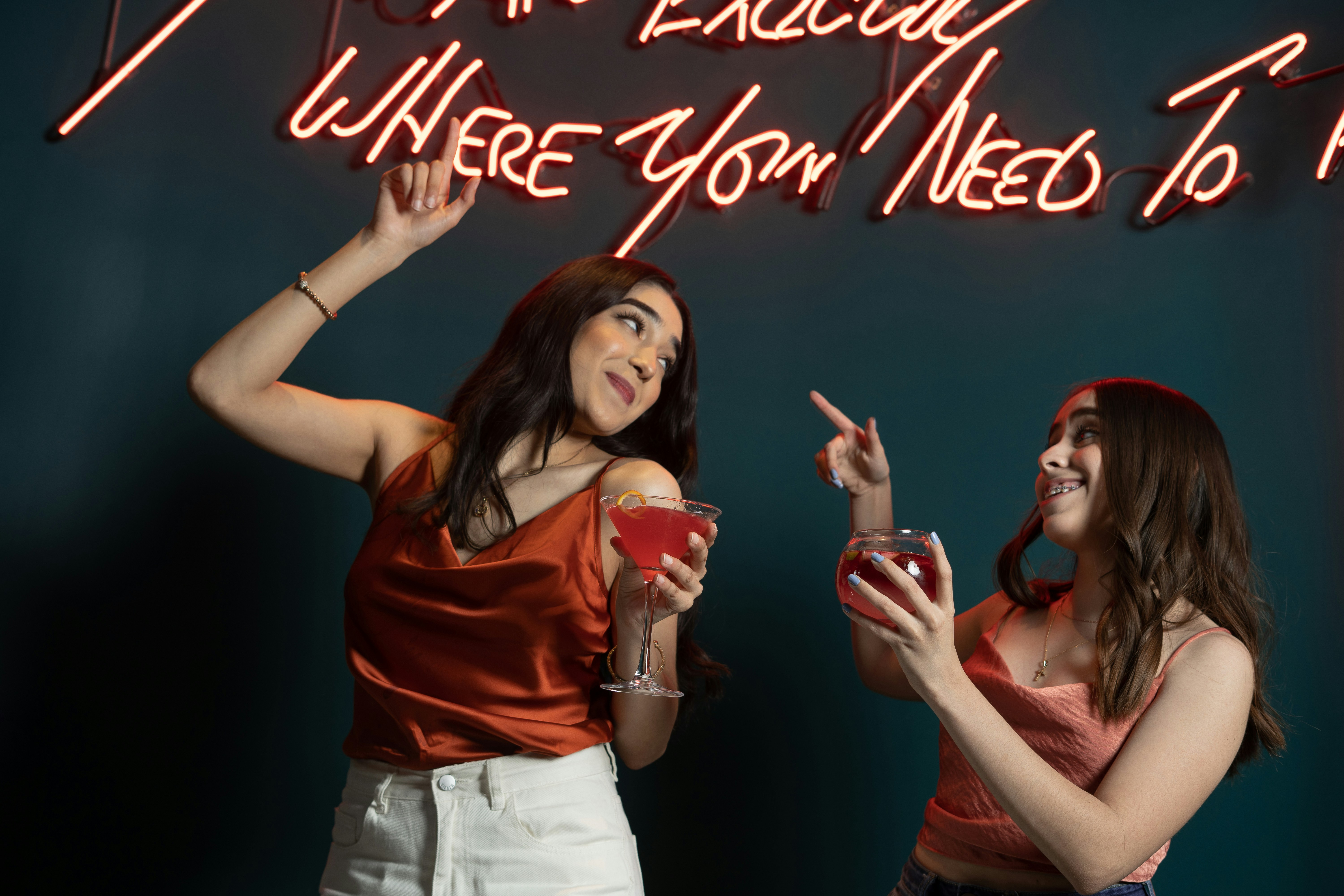 two women standing in front of a neon sign