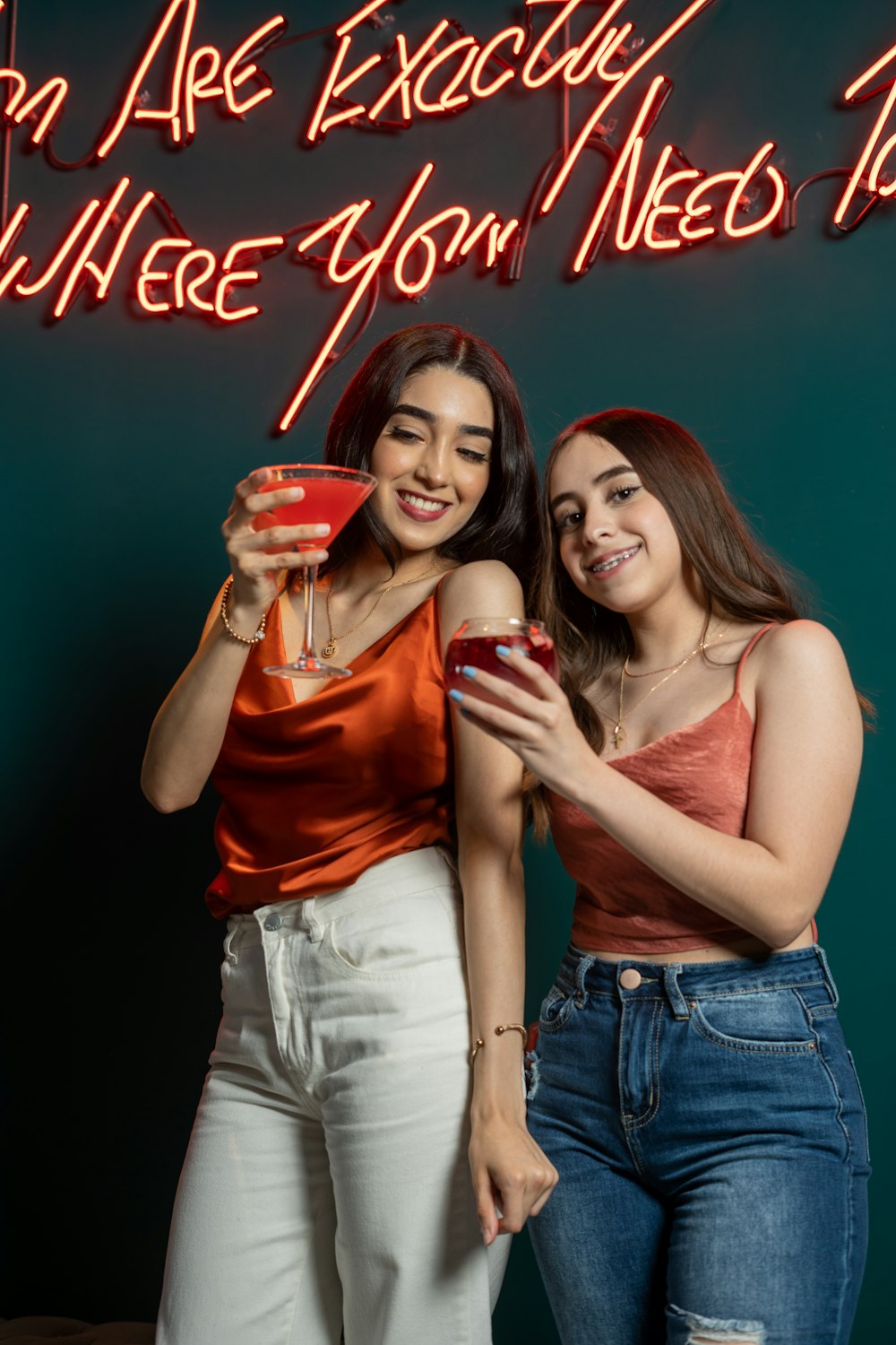 two women standing next to each other holding drinks