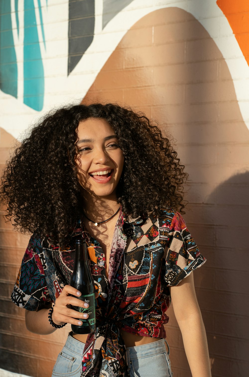 a woman with curly hair holding a bottle of beer