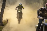 Off-road bike maneuvering rugged terrain with dust clouds.