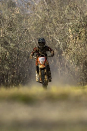 Dynamic shot of a rider wearing full protection gear racing through a forest trail.