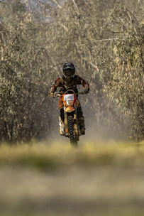 Dynamic shot of a rider wearing full protection gear racing through a forest trail.