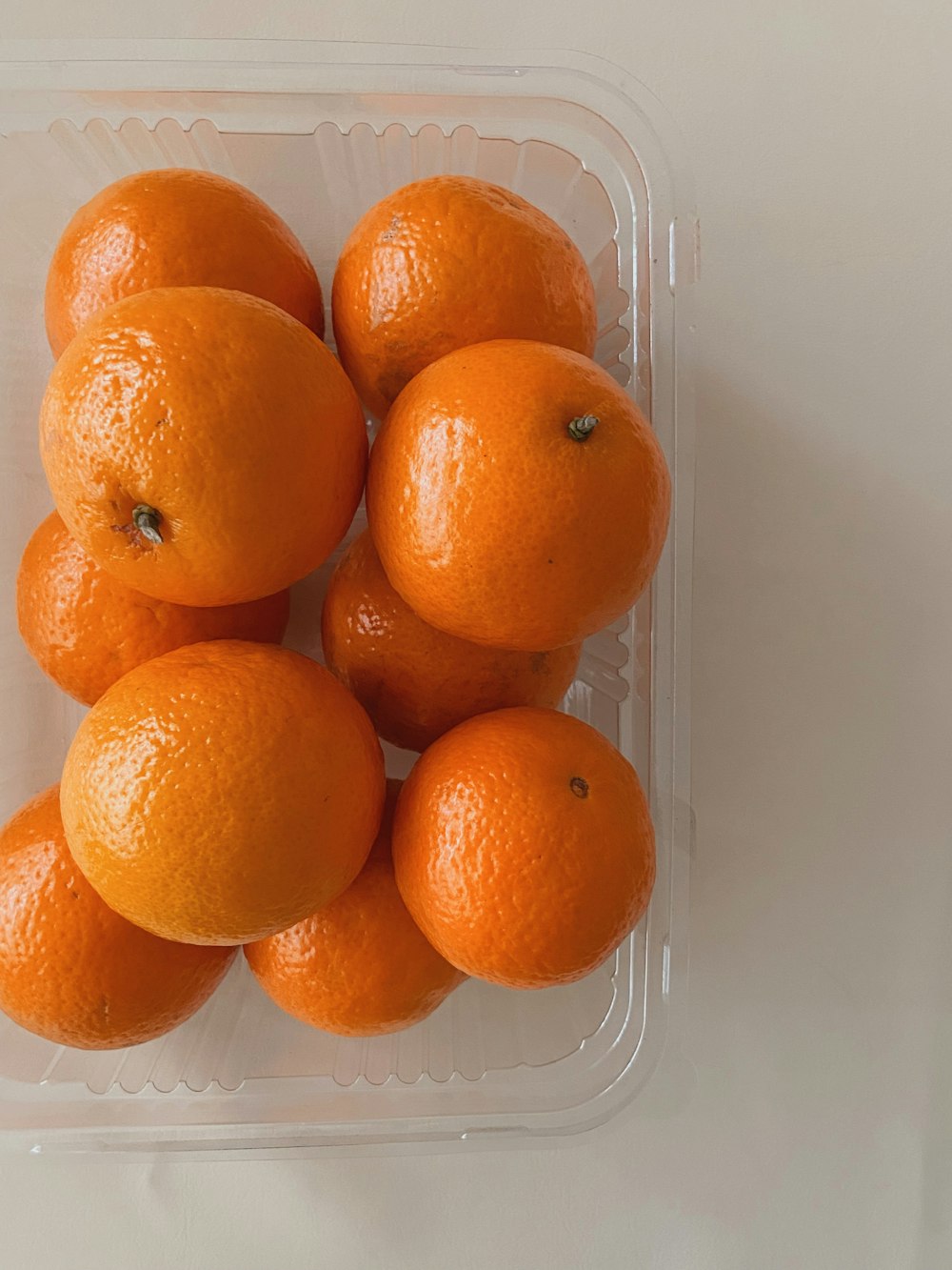 a plastic container filled with oranges on top of a table