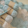 three balls of yarn and a crochet hook on a blanket
