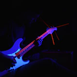 A moody cinematic shot of Juan Carlos Osnaya Jr. performing with electric blue and deep red lighting.