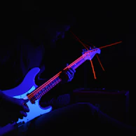Close-up of the lead guitarist shredding a solo with passion under moody blue lights.