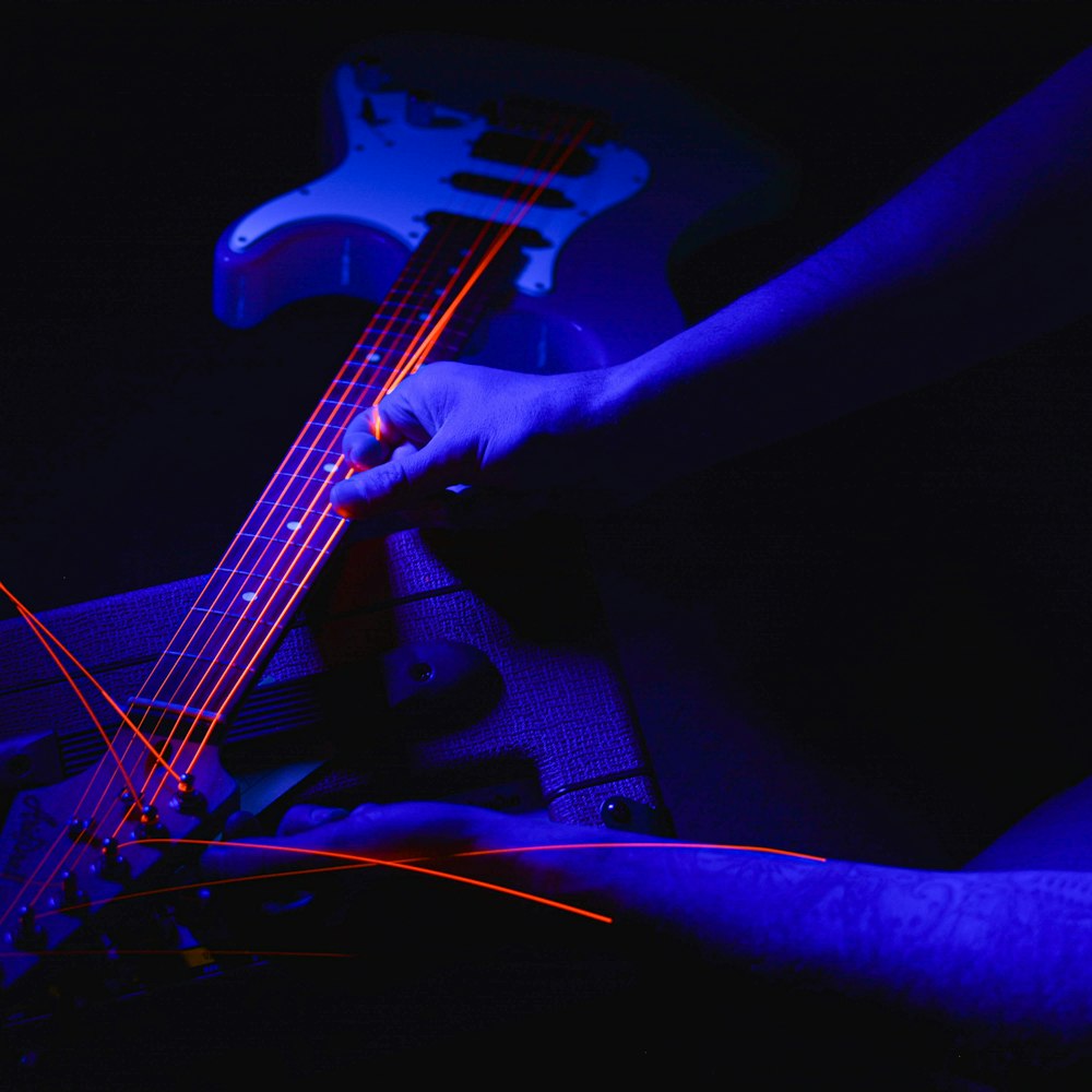 Una persona tocando una guitarra en una habitación oscura