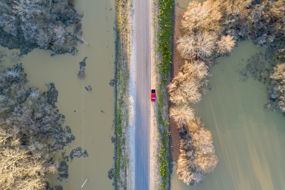 an aerial view of a red car driving down a road