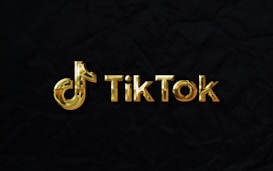 The image features a golden TikTok logo set against a dark, textured background.