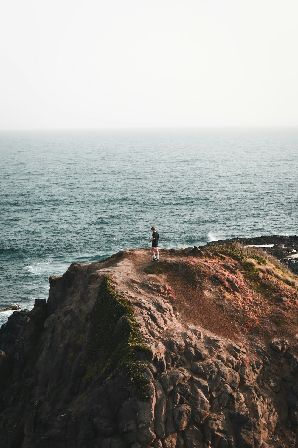 a person standing on top of a cliff near the ocean