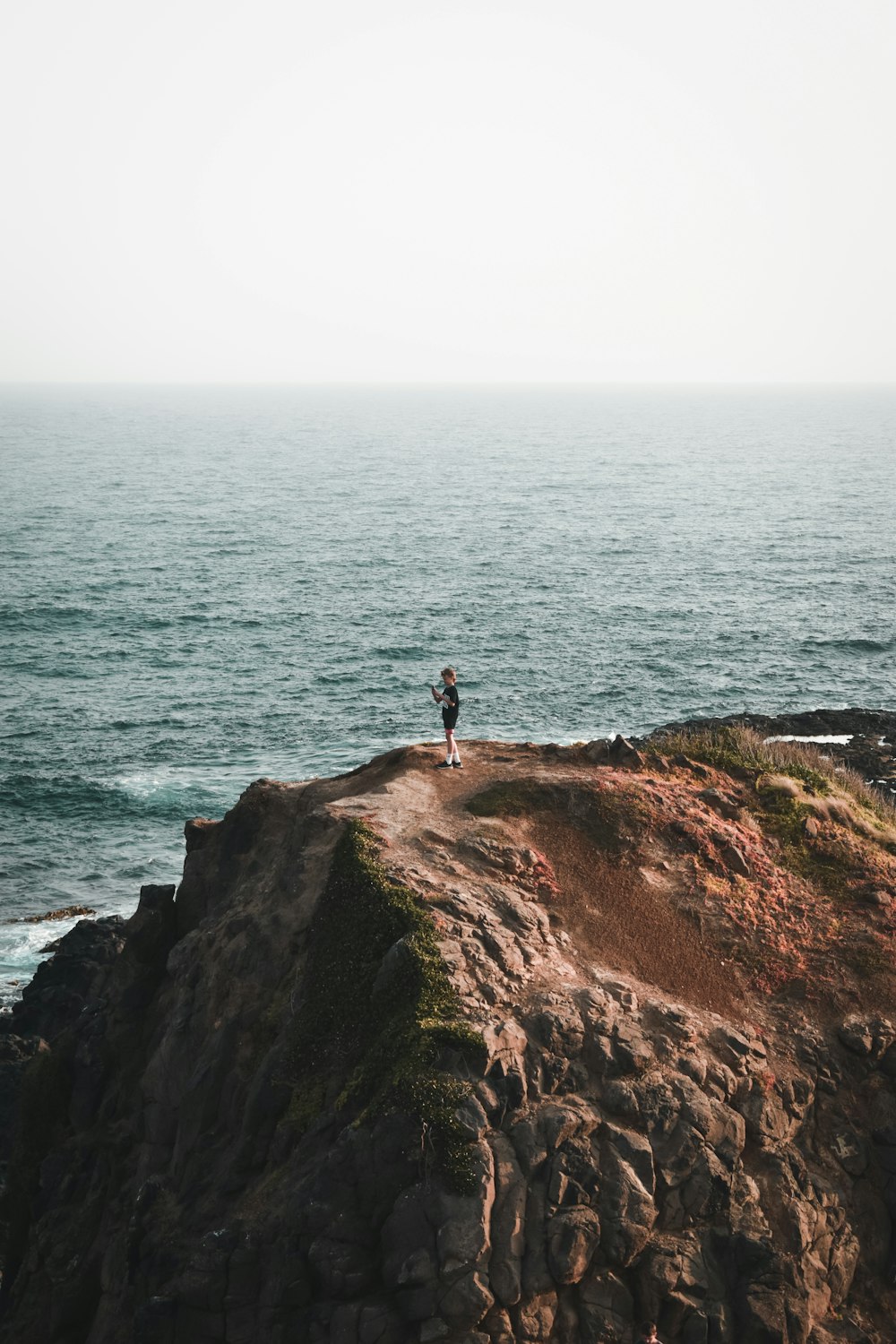 a person standing on top of a cliff near the ocean