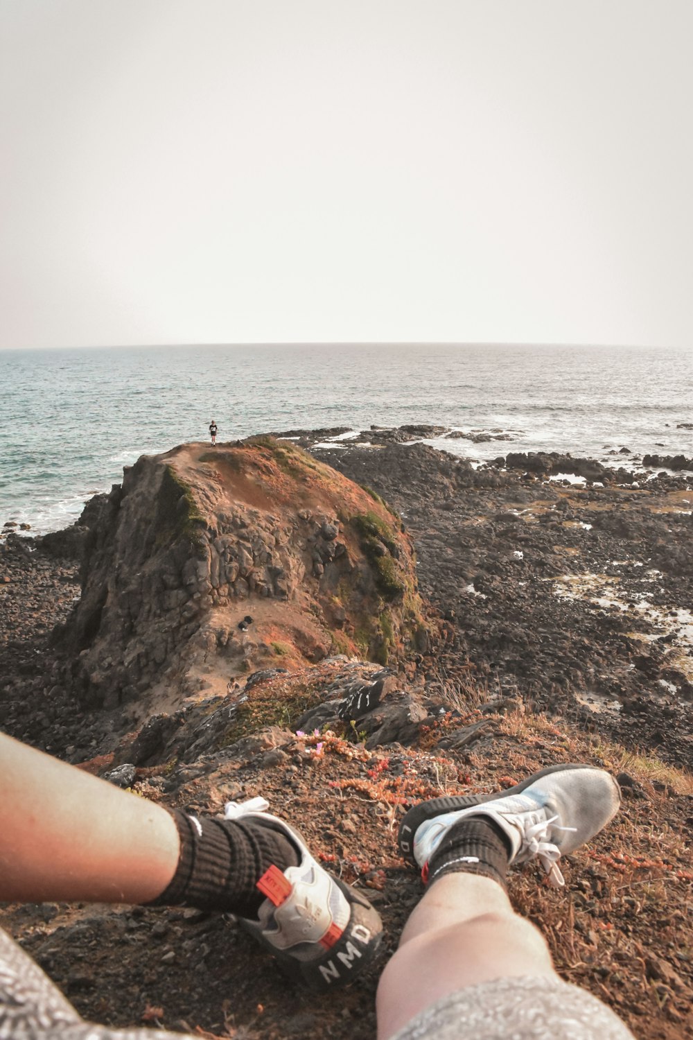 a person sitting on a rock near the ocean